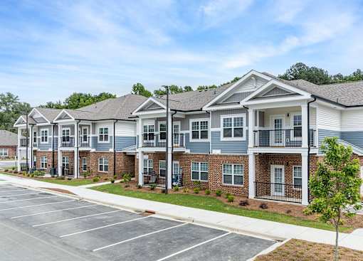 A row of townhouses with a parking lot in front.