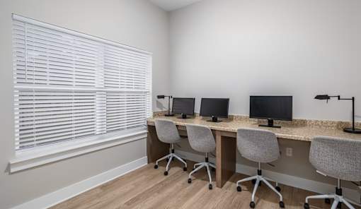 A room with four desks and chairs arranged in a row.