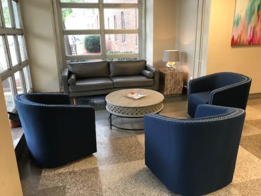 A living room with a grey couch, two blue chairs and a coffee table at Highland Memorial, NC