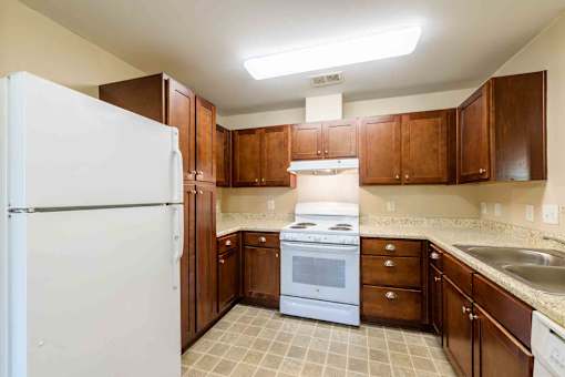 A kitchen with brown cabinets and a white refrigerator.
