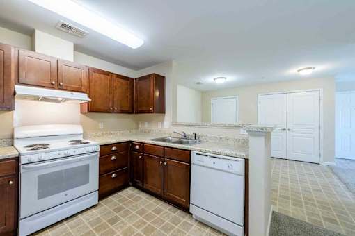 A kitchen with white appliances and brown cabinets.