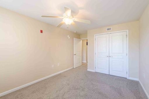 A room with a ceiling fan and carpeted floor.