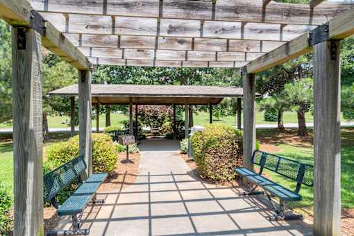 A wooden pergola with green benches is in a park.at Greylin Ridge Apartments, Statesville