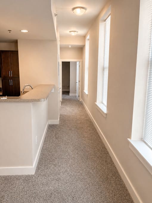 A long hallway with a white counter on the side and a brown cabinet.