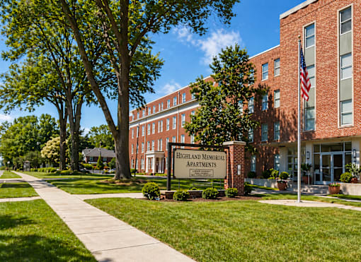 A brick building with a sign that says Highland Memorial Apartments.