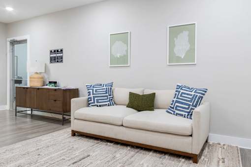 A white couch with blue and green pillows sits in a room with a wooden floor and two framed pictures on the wall at James Lewis Jr, Charleston