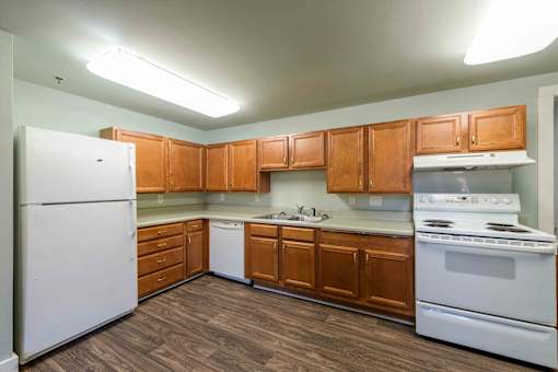 A kitchen with white appliances and wooden cabinets.at Kinston Hotel Apartments, Kinston North Carolina