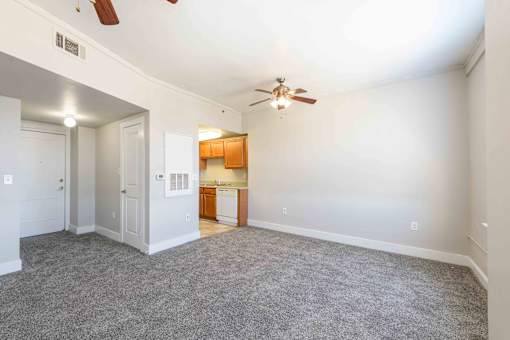 A room with a ceiling fan and a kitchen area in the background.at Kinston Hotel Apartments, Kinston, 28501
