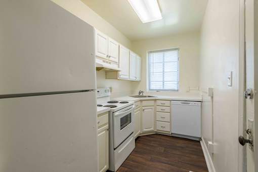 A kitchen with white appliances and wooden floors.at Kinston Oaks Apartments, Kinston, NC