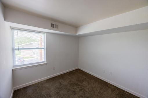 A room with a window and carpeted floor.