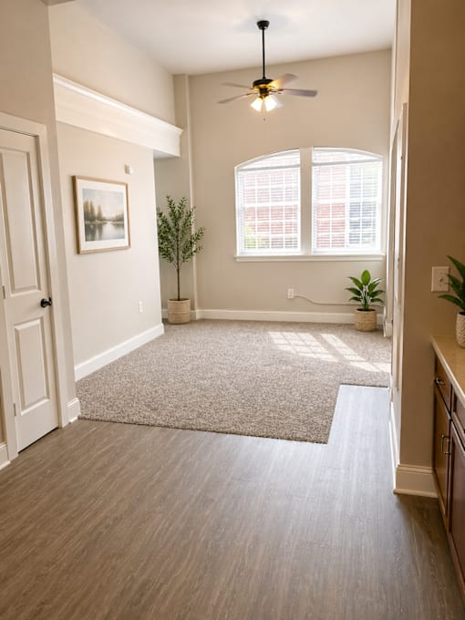 A room with a ceiling fan and a rug on the floor.