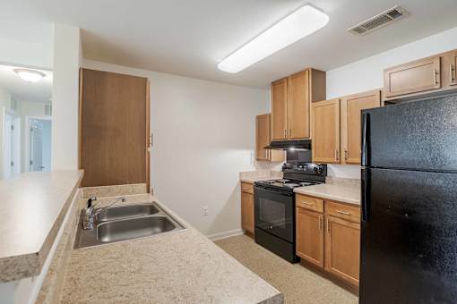 A kitchen with black appliances and wooden cabinets.