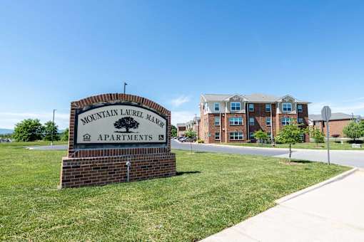 A sign for Mountain Laurel Manor Apartments stands in front of a building. at Mountain Laurel III Apartments, Staunton, VA, 24401