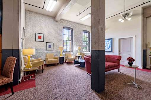 A living room with a red carpet and a red couch at Nantucket Lofts Apartments, Kinston, NC, 28501