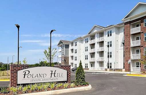 A sign for Poland Hill Senior Apartments is in front of a building.