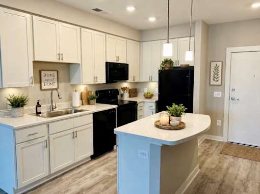 A kitchen with white cabinets and a black refrigerator.