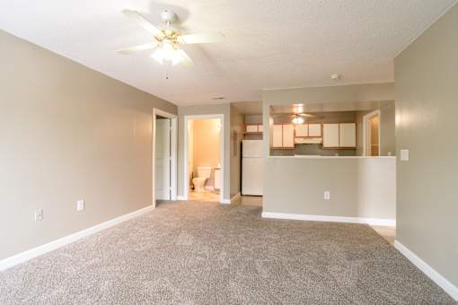 A living room with a carpeted floor and a ceiling fan.at Spaulding Woods Apartments, North Carolina, 28752