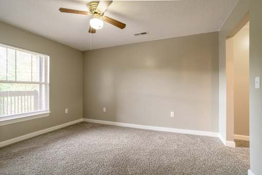 A room with a ceiling fan and carpeted floorat Spaulding Woods Apartments, North Carolina.