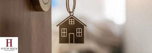 A house keychain hanging from a wooden door.