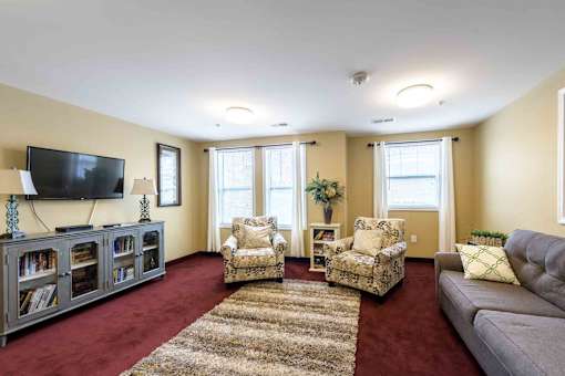 A living room with a television, two chairs, and a couch at The Grande at Granite Falls LLC Apartments, Rolesville