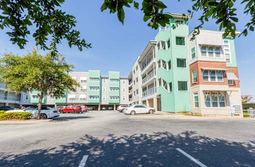 A street view of a multi-story building with cars parked in front.at West Yard Lofts, North Charlston, SC