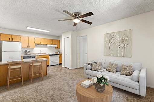 A living room with a couch, a dining table, and a ceiling fan.