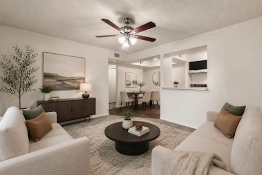 A living room with a white couch, a coffee table, and a ceiling fan.