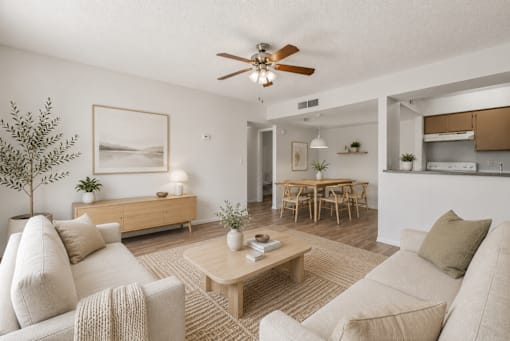 A living room with a beige couch, a coffee table, and a ceiling fan.