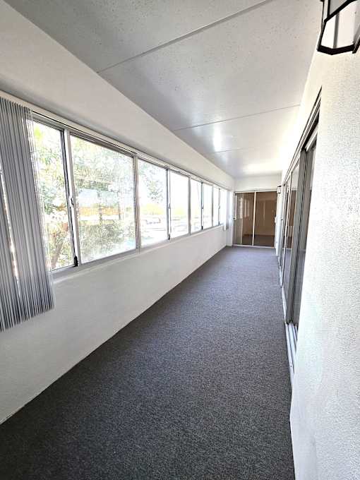 A long hallway with a carpeted floor and white walls.