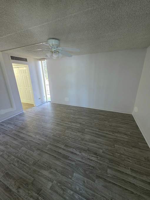 A room with a ceiling fan and wood flooring.