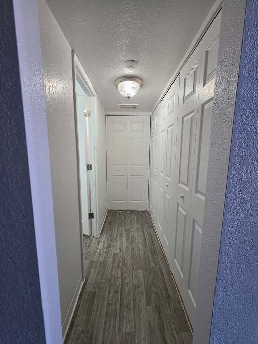 A long hallway with white doors and a light on the ceiling.