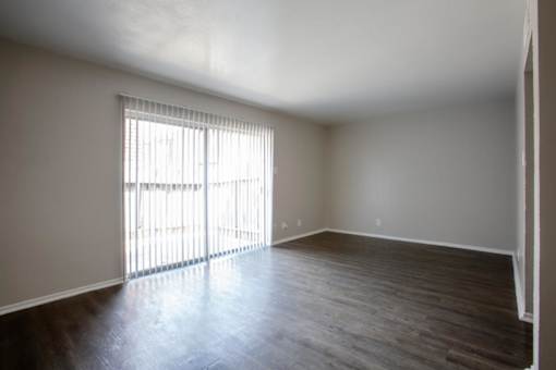 A room with wooden floors and a window with blinds.