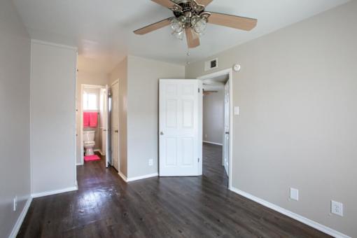 A room with a ceiling fan and wooden floors.