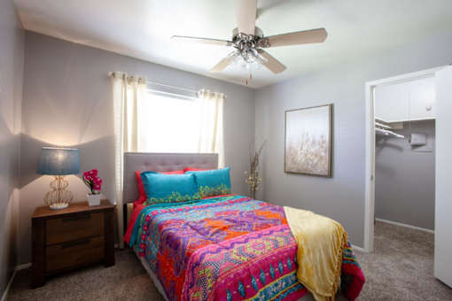A bedroom with a bed, nightstand, and a ceiling fan.