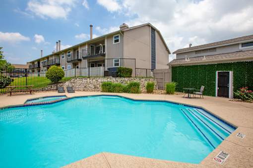 A swimming pool in a residential area with a green wall on the right.