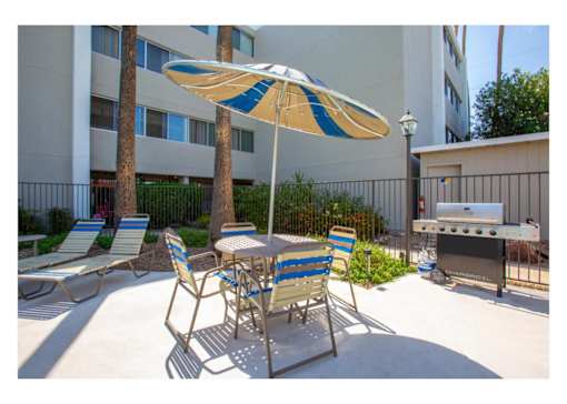 A patio with a table, chairs and an umbrella.