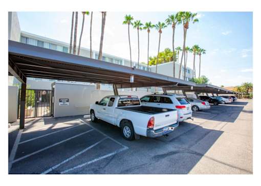 A parking lot with a white truck parked under a canopy.