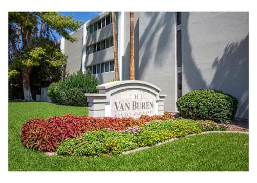 A sign for The Van Buren Apartments is in front of a building.