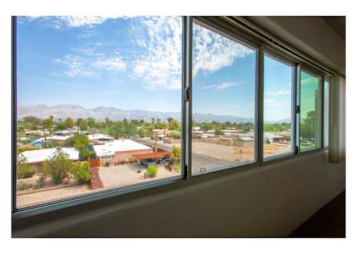 A view of a landscape from a window with a building in the distance.