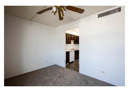 A room with a ceiling fan and carpeted floor.