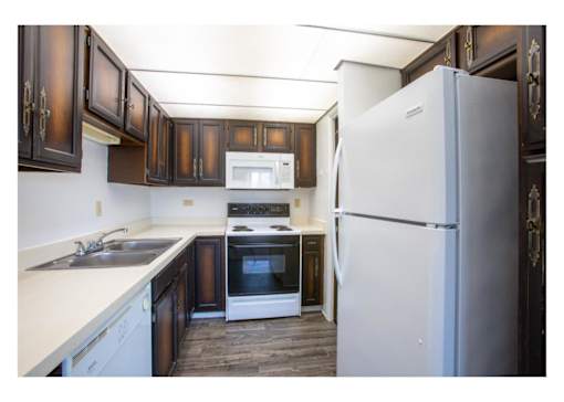 A kitchen with a white refrigerator and brown cabinets.