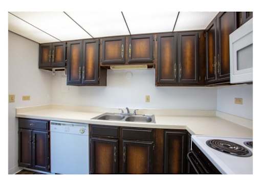 A kitchen with brown cabinets and white appliances.