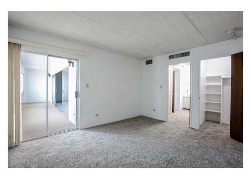 A room with white walls and carpeted floor with a sliding glass door.
