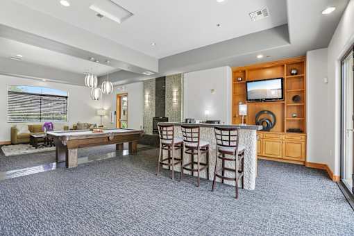 A spacious living room with a bar area and a television.