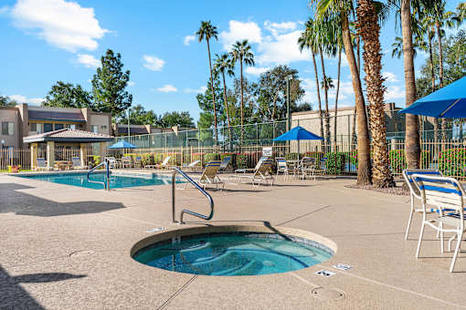 A pool area with a hot tub and lounge chairs.