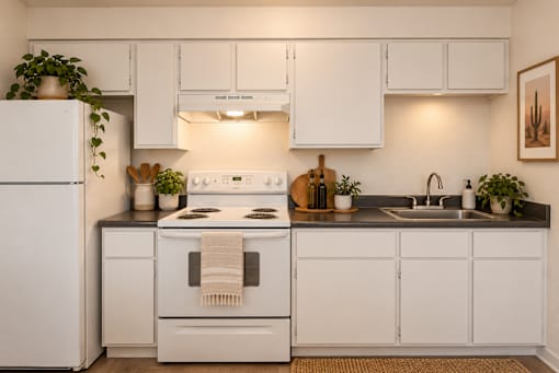 A white kitchen with a stove top oven and a sink.