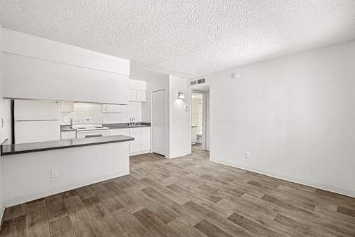 A kitchen with white cabinets and a wooden floor.