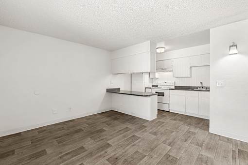 A kitchen with white cabinets and a wooden floor.