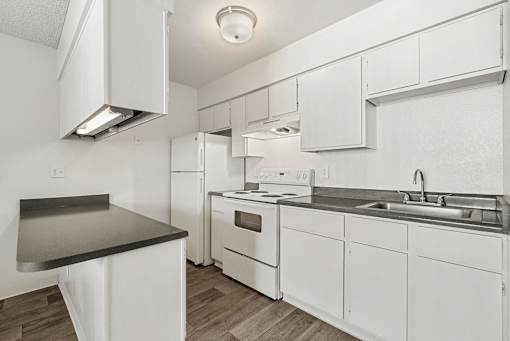 A white kitchen with a black counter top.