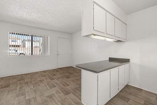 A kitchen with white cabinets and a wooden floor.